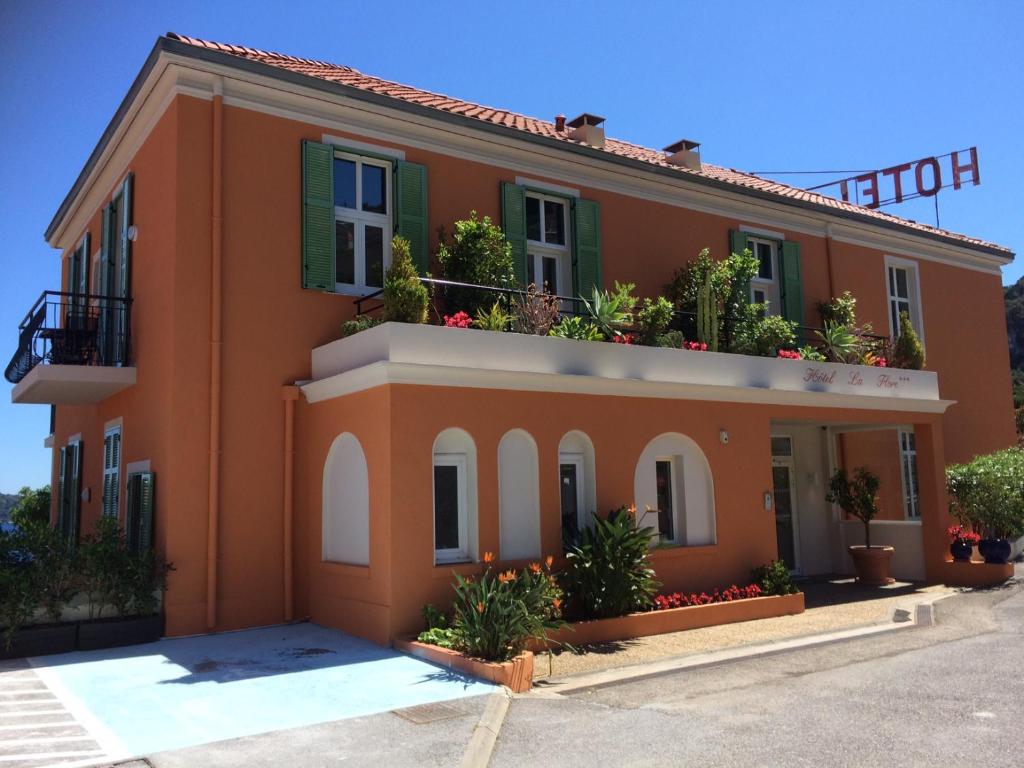 an orange building with flowers on the balconies at Hôtel La Flore in Villefranche-sur-Mer
