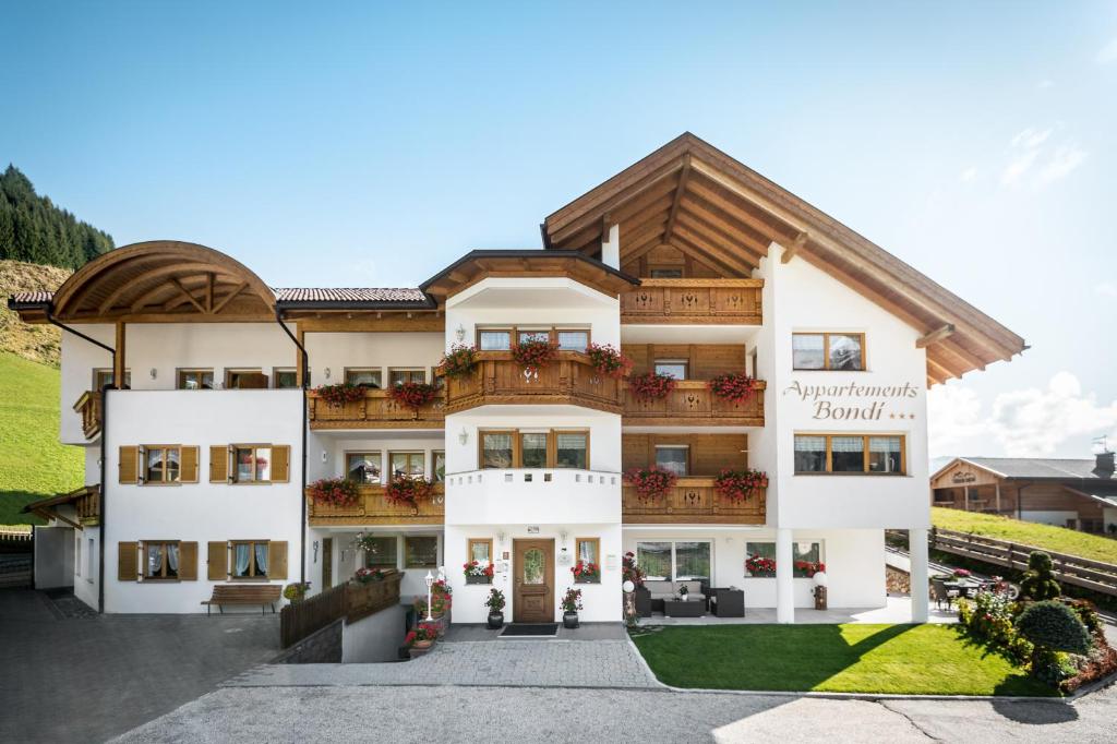duży biały budynek z drewnianym dachem w obiekcie Residence Bondì w mieście Colfosco
