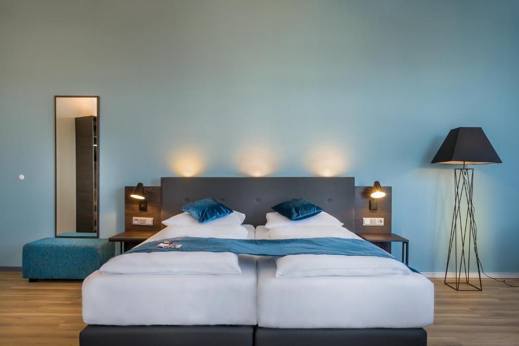 a bedroom with two beds and a blue wall at Novum Hotel Ruf Pforzheim in Pforzheim