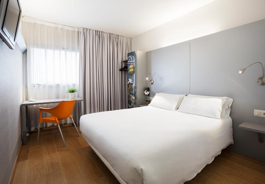 Habitación de hotel con cama blanca grande y escritorio. en B&B HOTEL Figueres, en Figueres