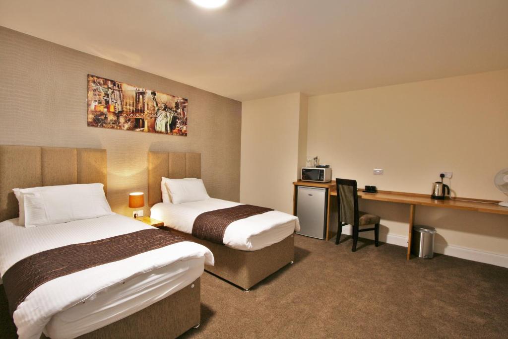 a hotel room with two beds and a desk at New County Hotel & Serviced Apartments by RoomsBooked in Gloucester
