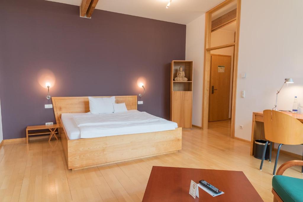 ein Schlafzimmer mit einem Bett und einem Tisch in einem Zimmer in der Unterkunft Hotel Kongressissimo in Vilsbiburg