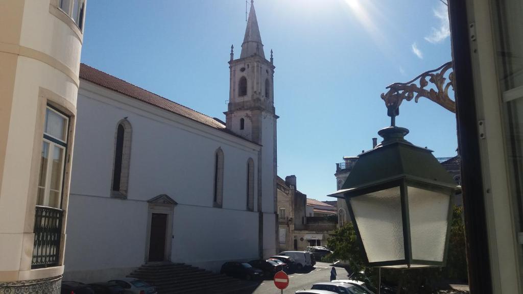 a church with a steeple and a street with a lamp at Casa de Marvila in Santarém