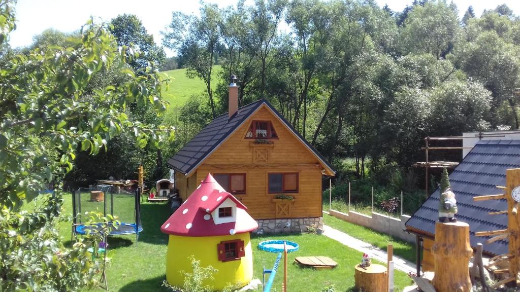 a small wooden house with a playground in the yard at Chata Emka in Vyšný Kubín