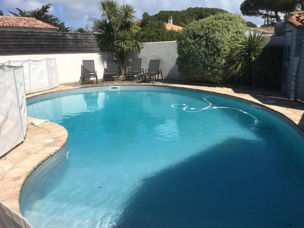 a large blue swimming pool with chairs in a yard at L'Avocette in Le Bois-Plage-en-Ré