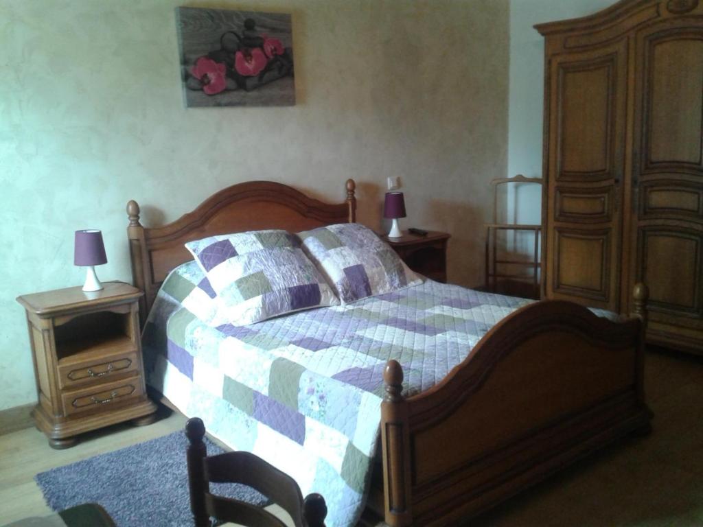 ein Schlafzimmer mit einem Bett mit einem Holzrahmen und einer Kommode in der Unterkunft Domaine de la Rue in La Berthenoux