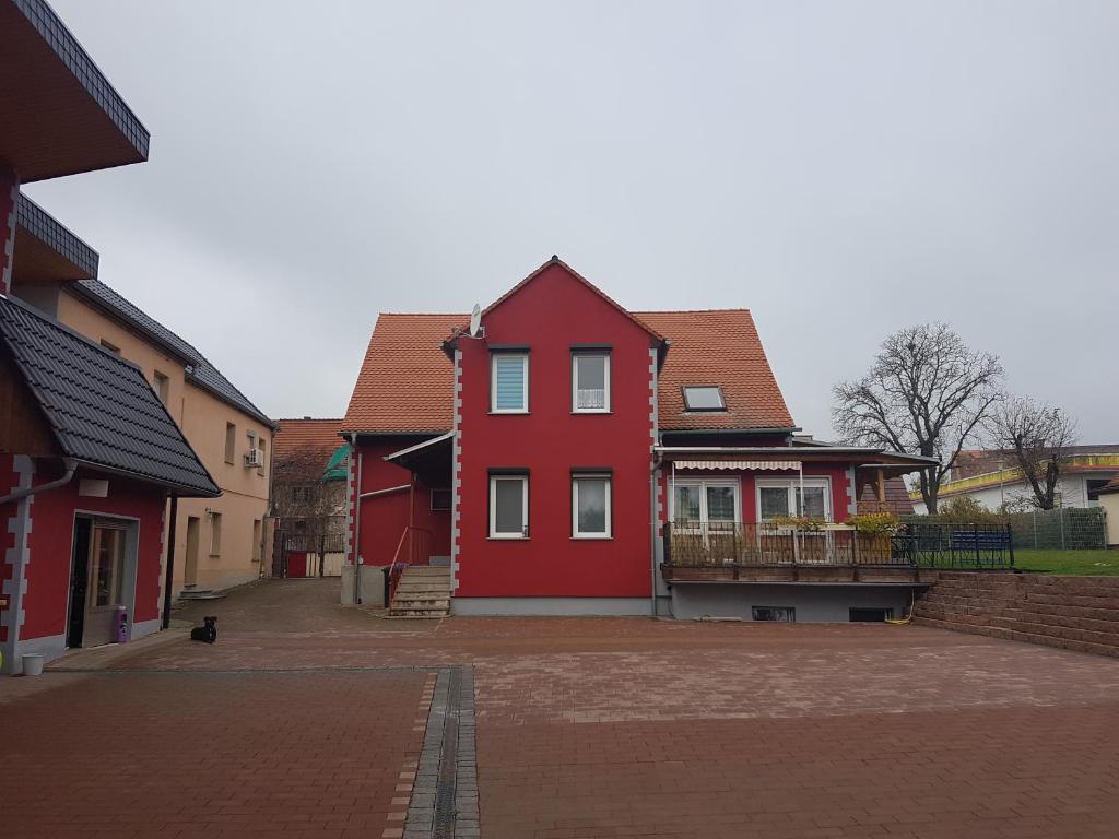 ein rotes Haus in einer Backsteinstraße mit Gebäuden in der Unterkunft Ferienapartment Meiss in Erdeborn