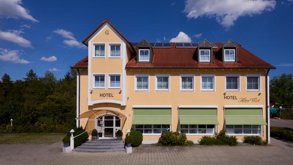 duży żółty budynek z czerwonym dachem w obiekcie Hotel Alter Wirt w mieście Hallbergmoos
