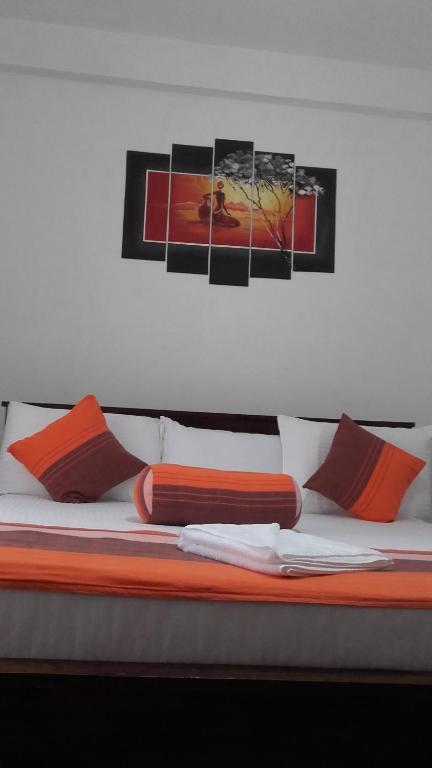 a bed with orange pillows and paintings on the wall at The European Gate - Anuradhapura in Anuradhapura
