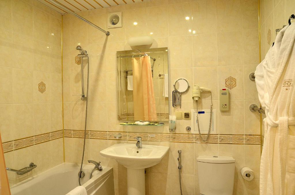 a bathroom with a tub, sink and mirror at Congress Hotel Forum in Ryazan