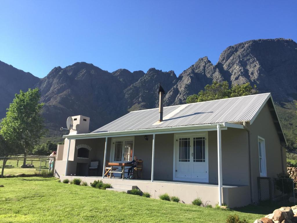 a small house with mountains in the background at Olive Cottage in Franschhoek