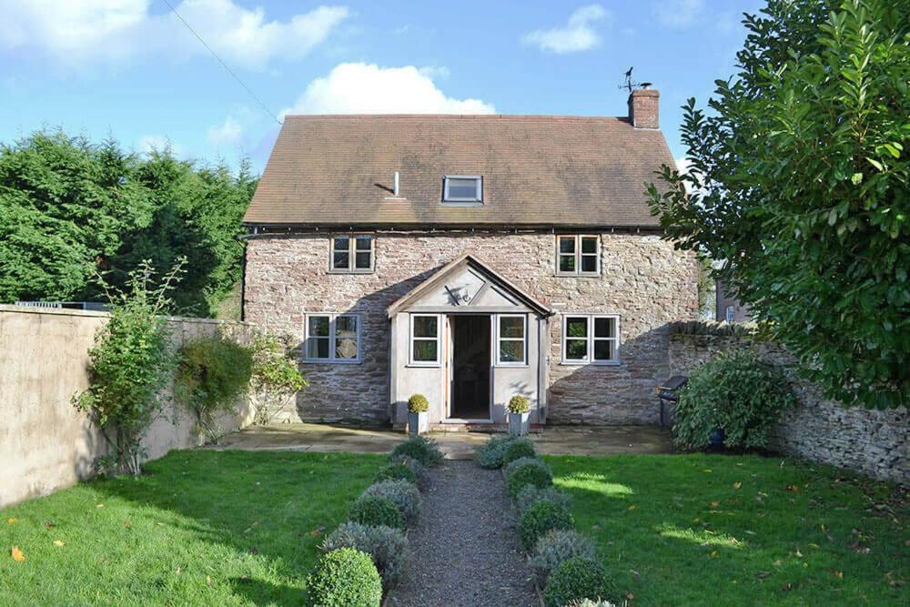 una vieja casa de piedra con una puerta y un patio en Hampton Wafre Cottage, en Docklow