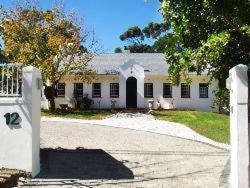 a large white house with a driveway in front of it at KaapsePracht Bed & Breakfast in Somerset West