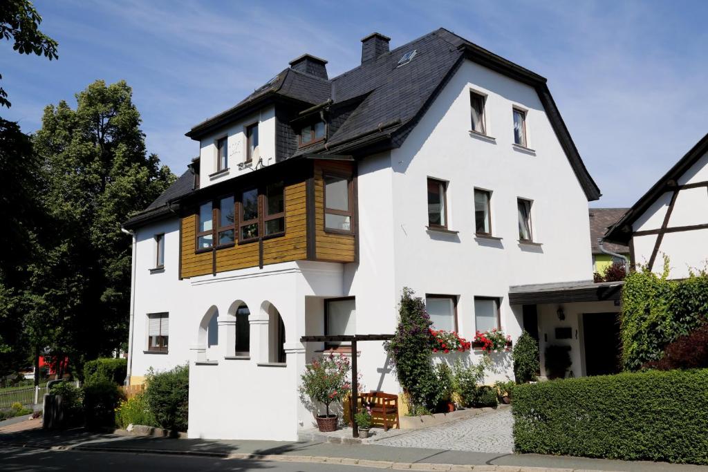 ein weißes Haus mit schwarzem Dach in der Unterkunft Ferienwohnung "Am Eisenbühl" in Berg