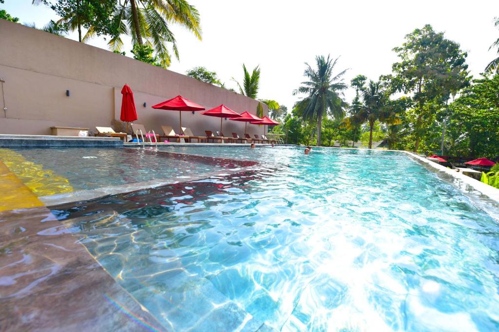 a large swimming pool with red umbrellas and chairs at Ballena Regency in Mirissa