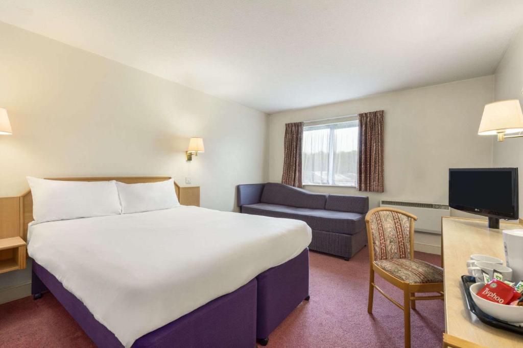 a hotel room with two beds and a television at Days Inn Chesterfield - Tibshelf in Tibshelf