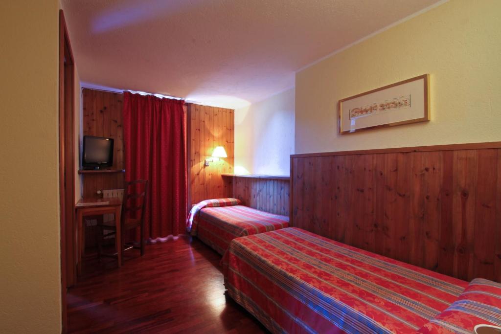 a hotel room with two beds and a television at Hotel Dolonne in Courmayeur