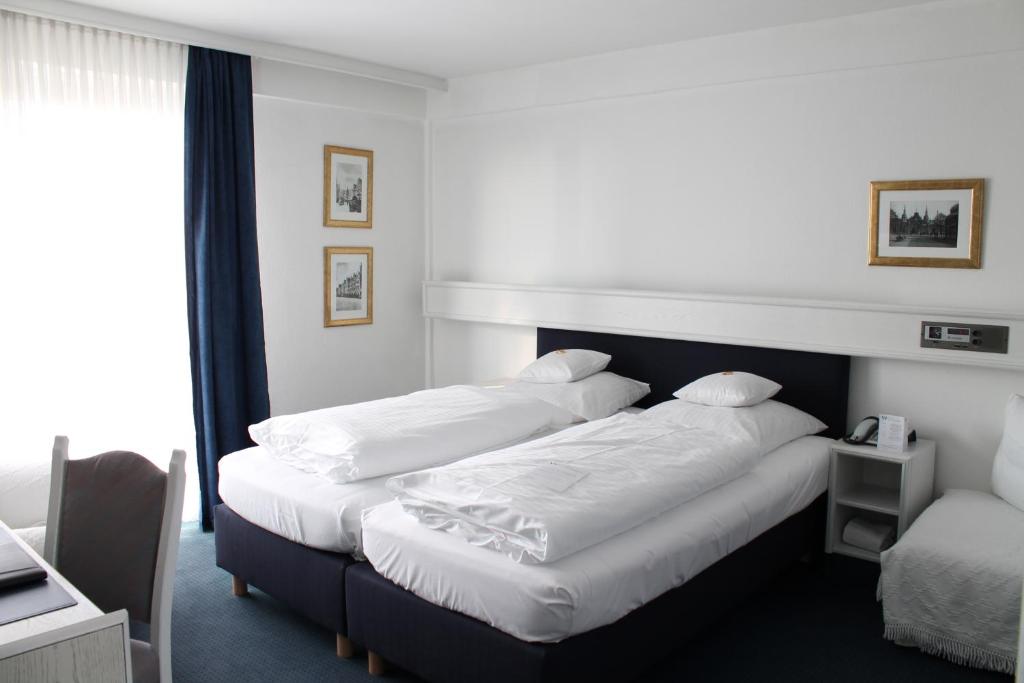 a hotel room with two beds and a window at Hotel Windthorst in Münster