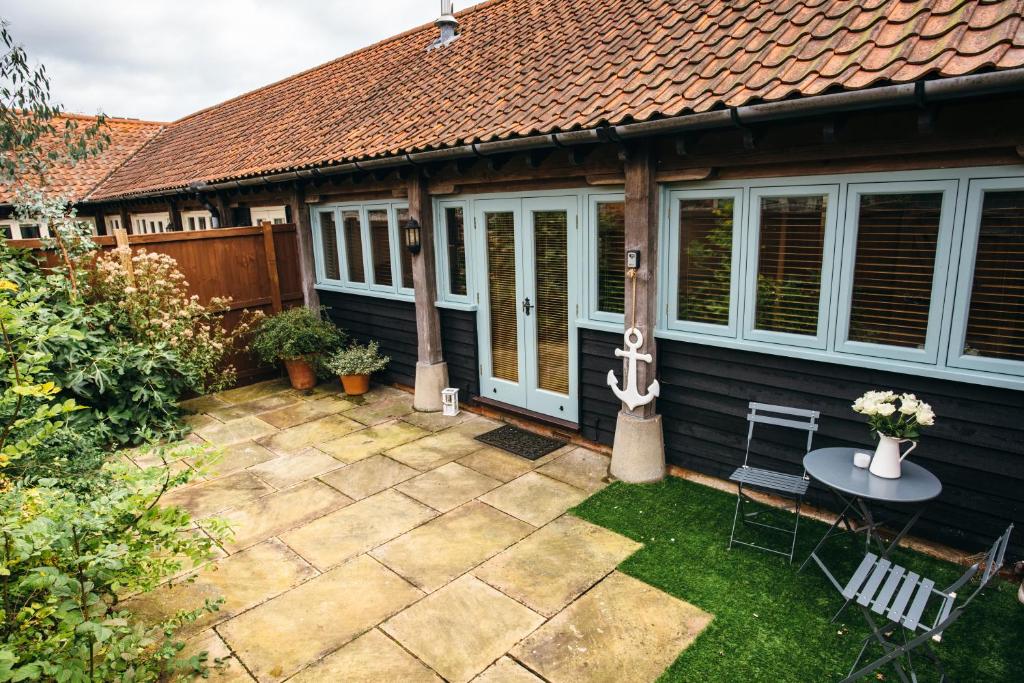 a patio with a table and chairs in front of a house at 7 Grove Farm Barns in Sculthorpe