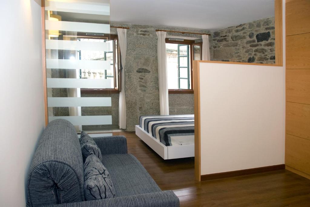 salon z kanapą i łóżkiem w obiekcie Apartamentos Domus Stellae w Santiago de Compostela