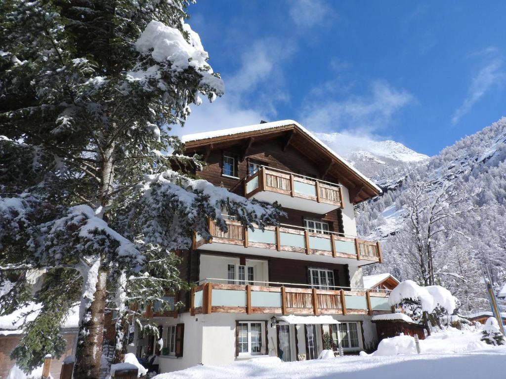 a building in the snow with snow covered trees at Haus Alpenperle in Saas-Almagell
