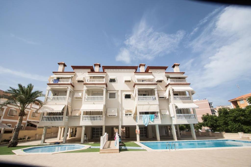 a large white building with a pool in front of it at Apartamento Costa Azahar in Santa Pola
