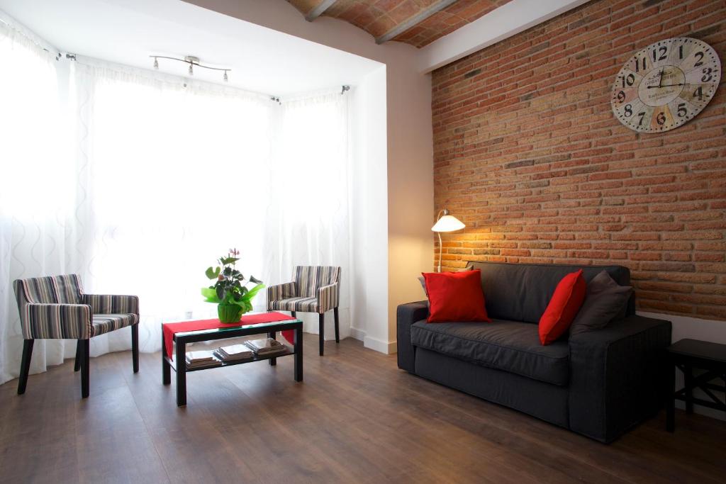 sala de estar con sofá y pared de ladrillo en Barcelonaforrent Tucson Suites, en Barcelona