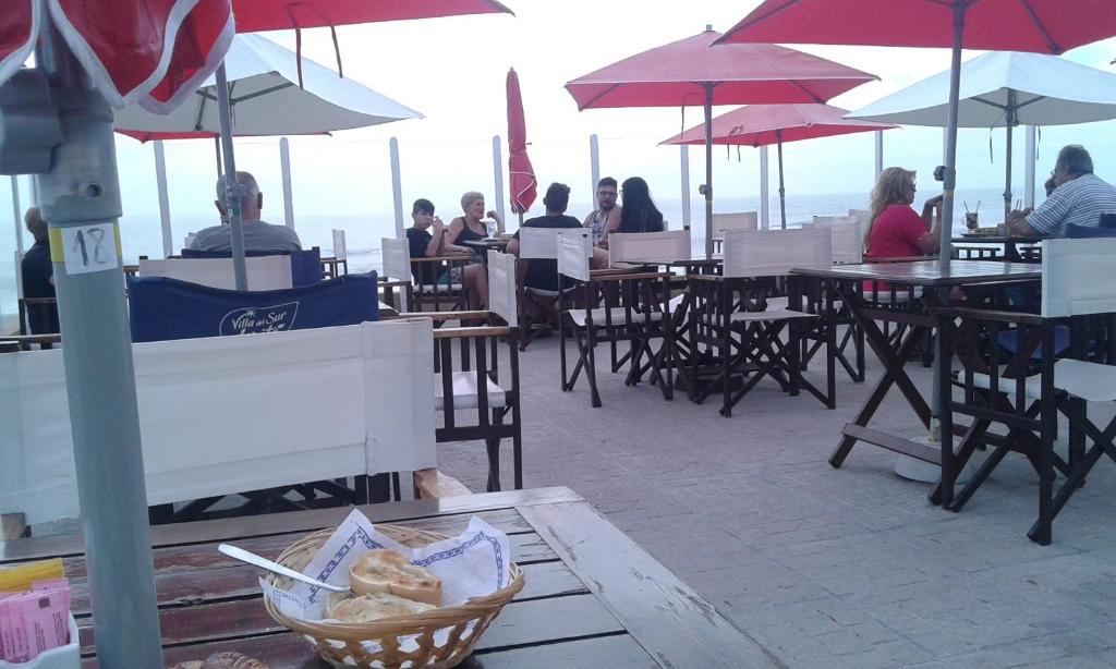 Un grupo de personas sentadas en mesas con sombrillas. en Braba III, en San Bernardo