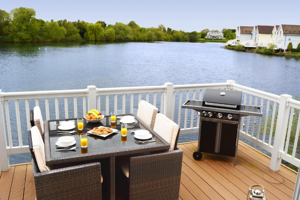 a table and chairs on a deck with a grill at Shelduck Lodge in South Cerney