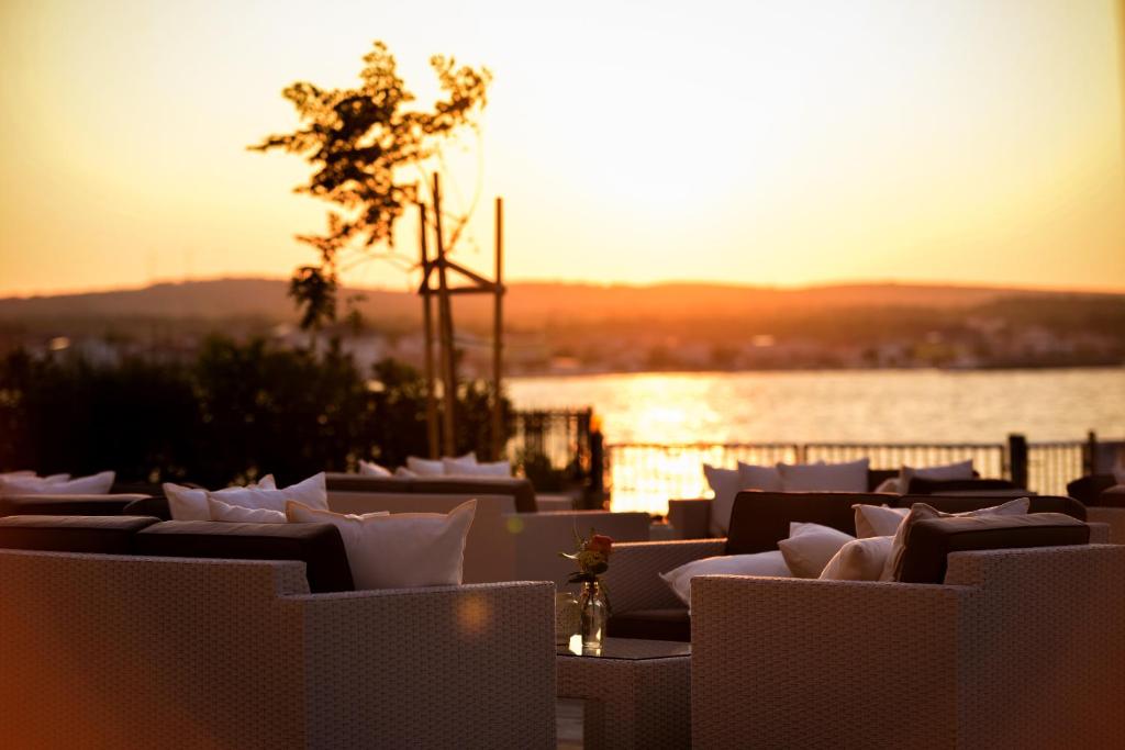 een groep witte stoelen met de zonsondergang op de achtergrond bij Sunset Deluxe Apartments in Vir