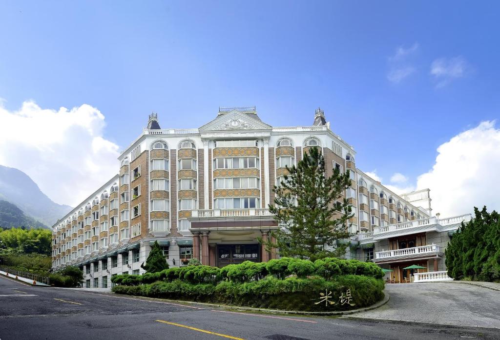 un grand bâtiment sur le côté d'une rue dans l'établissement Le Midi Hotel Chitou, à Lugu