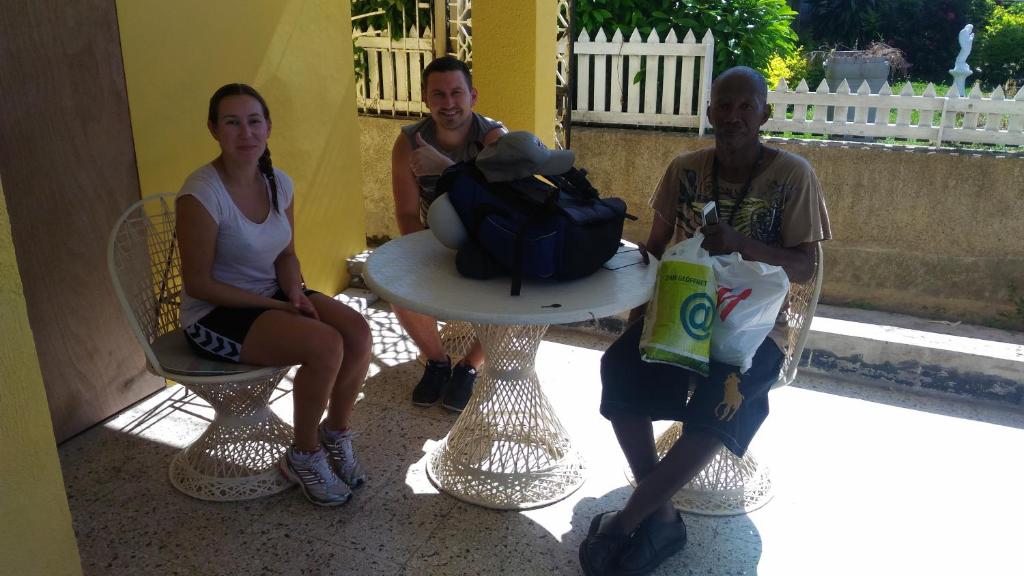 two men and a woman sitting around a table at Leslies' Home in Portmore