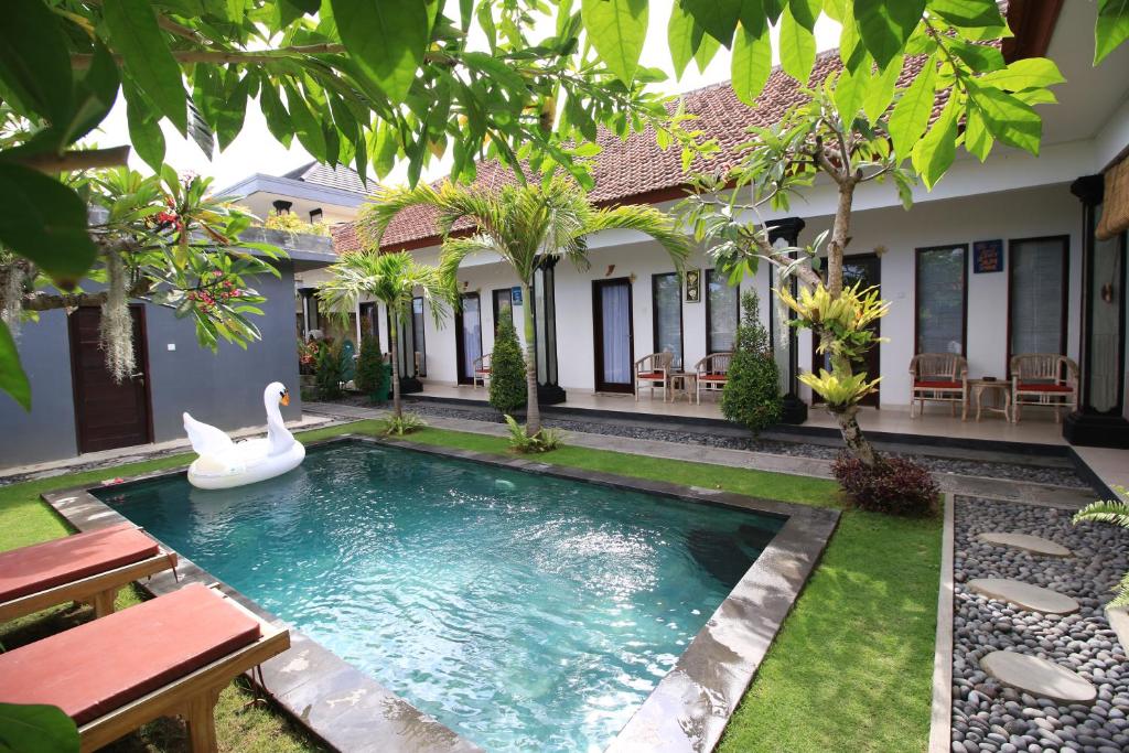 une piscine dans l'arrière-cour d'une maison avec un cygne dans l'eau dans l'établissement Surf Lodge Canggu, à Canggu