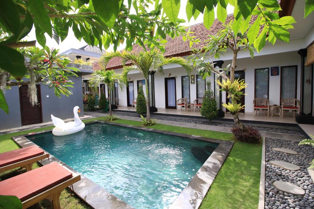 a pool in the backyard of a house with a swan in the water at Surf Lodge Canggu in Canggu
