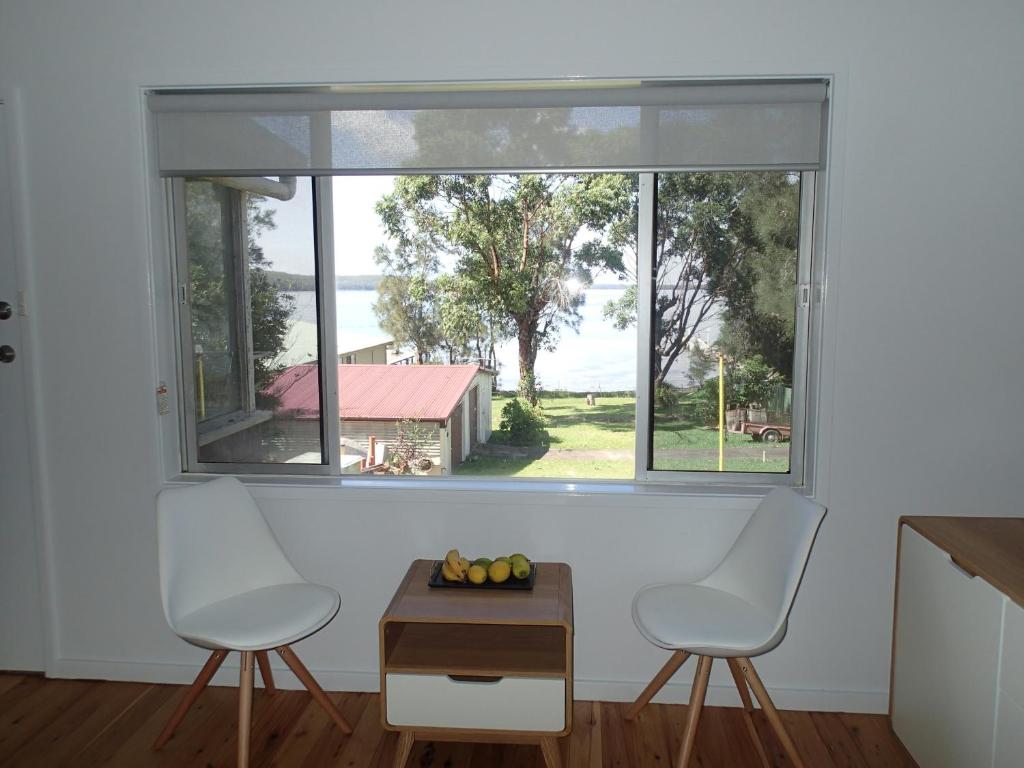 2 stoelen en een tafel in een kamer met een raam bij Glenrowan Erowal Bay in Erowal Bay