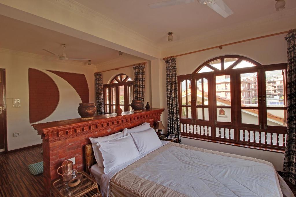 a bedroom with a bed in a room with windows at Vardan Resort n' Apartment in Pokhara