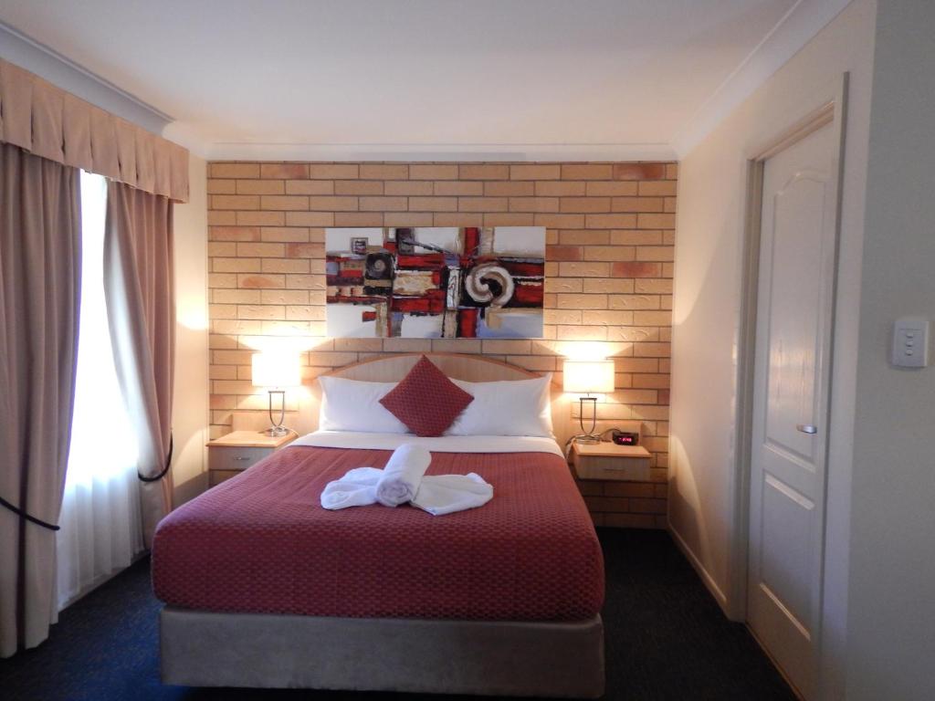 
a bedroom with a bed and a dresser at Cotswold Motor Inn in Toowoomba
