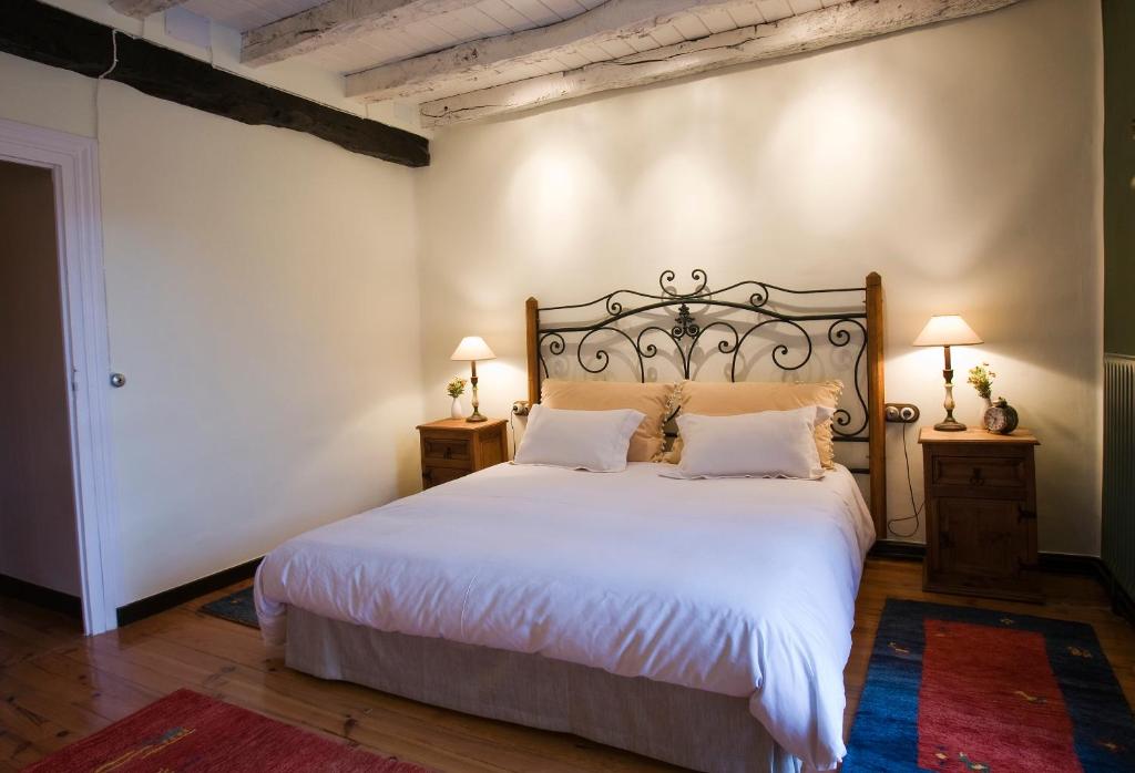 1 dormitorio con 1 cama blanca grande y 2 mesitas de noche en Casa Rural Mendiburu, en Osinaga