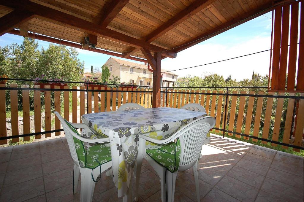 uma mesa e cadeiras num alpendre com um deque de madeira em Apartments Begic em Malinska