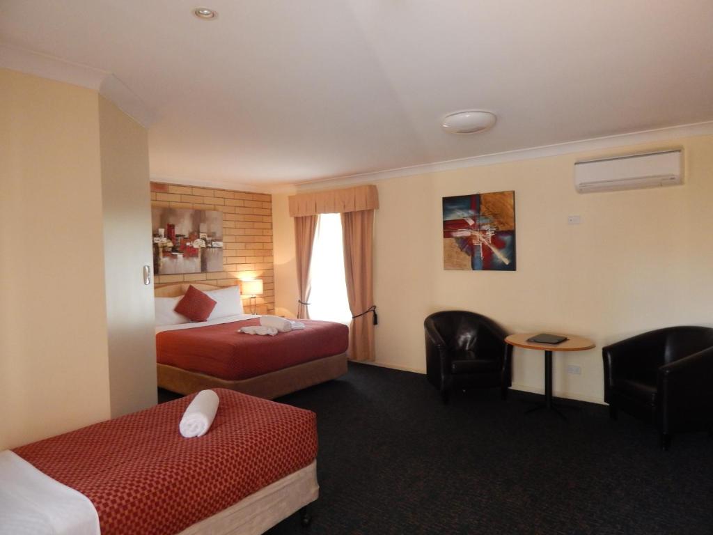 a hotel room with a bed and a desk at Cotswold Motor Inn in Toowoomba