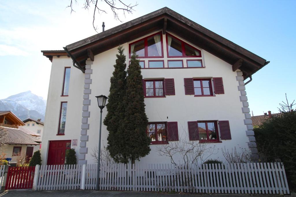 加爾米施－帕騰基興的住宿－Himmelschlösschen & Chalet Rose，白色的房子,设有红色的窗户和白色的围栏