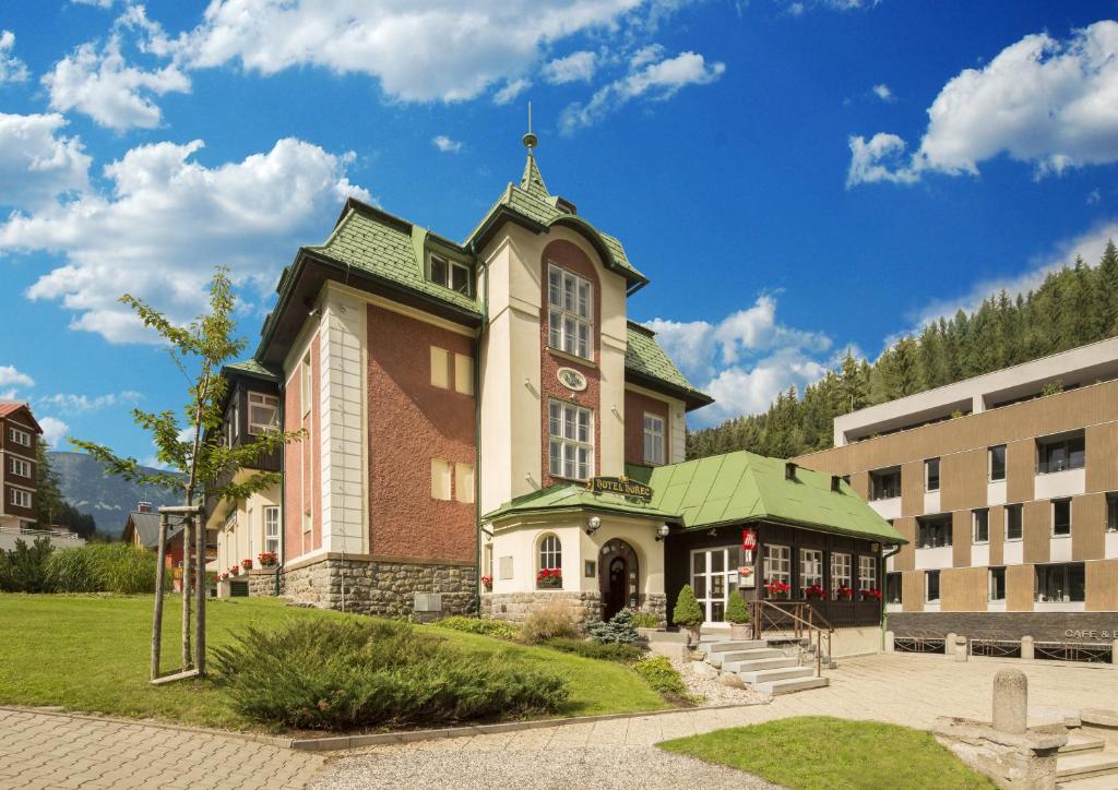 un bâtiment avec une tour d'horloge en haut dans l'établissement Hotel Hořec, à Pec pod Sněžkou