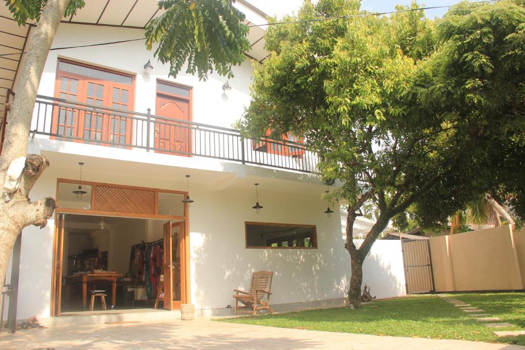 ein weißes Haus mit einem Balkon und einem Baum in der Unterkunft BoBo's Bed & Breakfast in Ahungalla