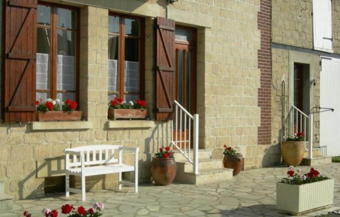 un banco blanco sentado fuera de un edificio con flores en Gite de la ferme du couvent, en Boran-sur-Oise