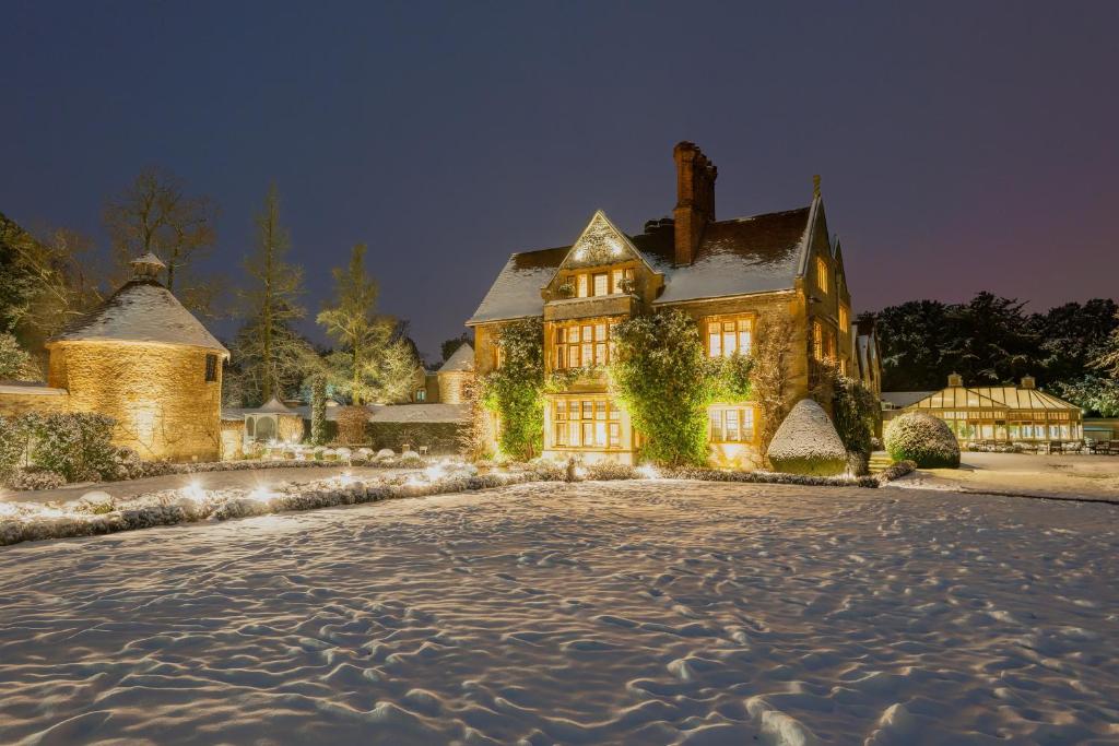 una casa grande en la nieve por la noche en Le Manoir aux Quat'Saisons, A Belmond Hotel, Oxfordshire en Great Milton