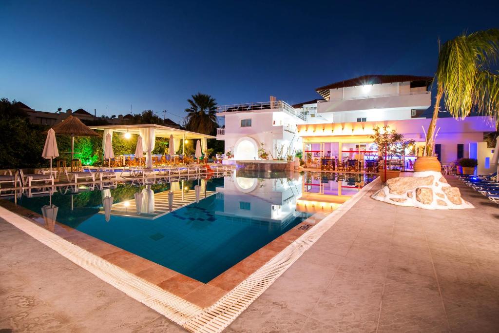 a hotel with a swimming pool at night at Tinas Plus Hotel in Faliraki