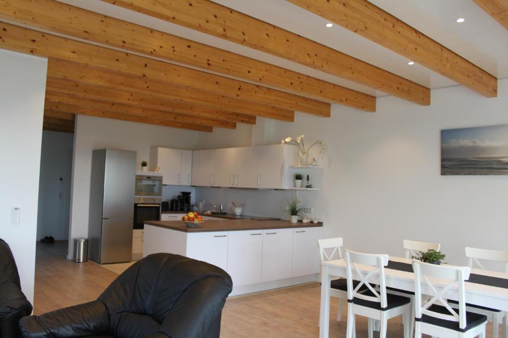 una cocina con armarios blancos y techos de madera. en Ferienwohnung Santore, en Kollmar