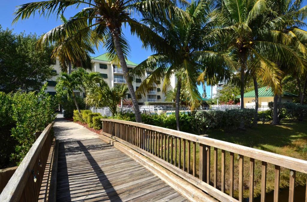 a wooden walkway with palm trees and a building at Sunrise Suites Antigua Suite #312 in Key West