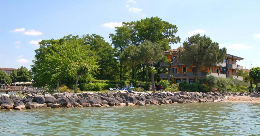 a group of rocks in the water next to a building at Albergo Il Biancospino in Sirmione