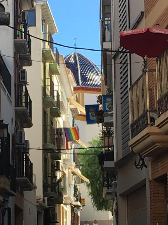 une ruelle étroite avec des bâtiments arborant des drapeaux arc-en-ciel et un bâtiment dans l'établissement Ed l' alcudia, à Benidorm